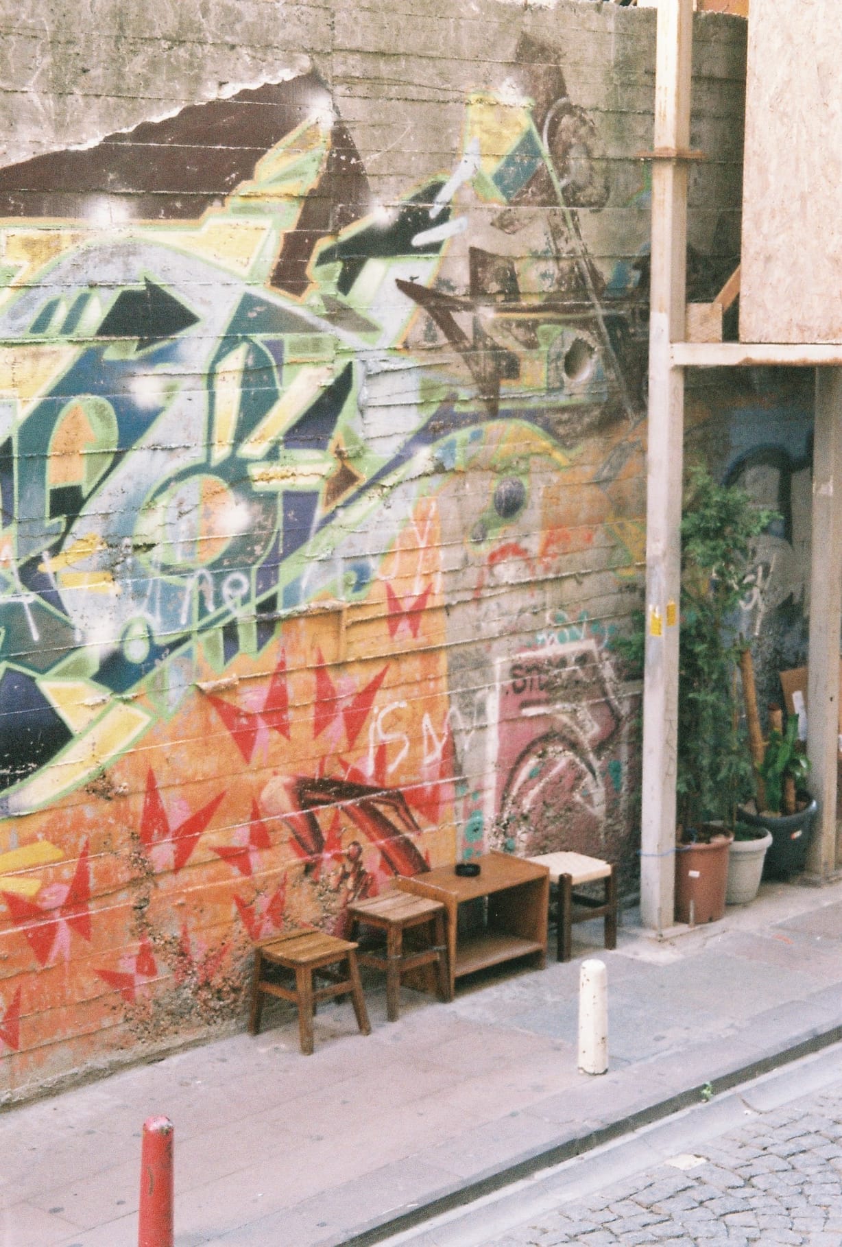 graffiti on wall with little wooden tables on the sidewalk