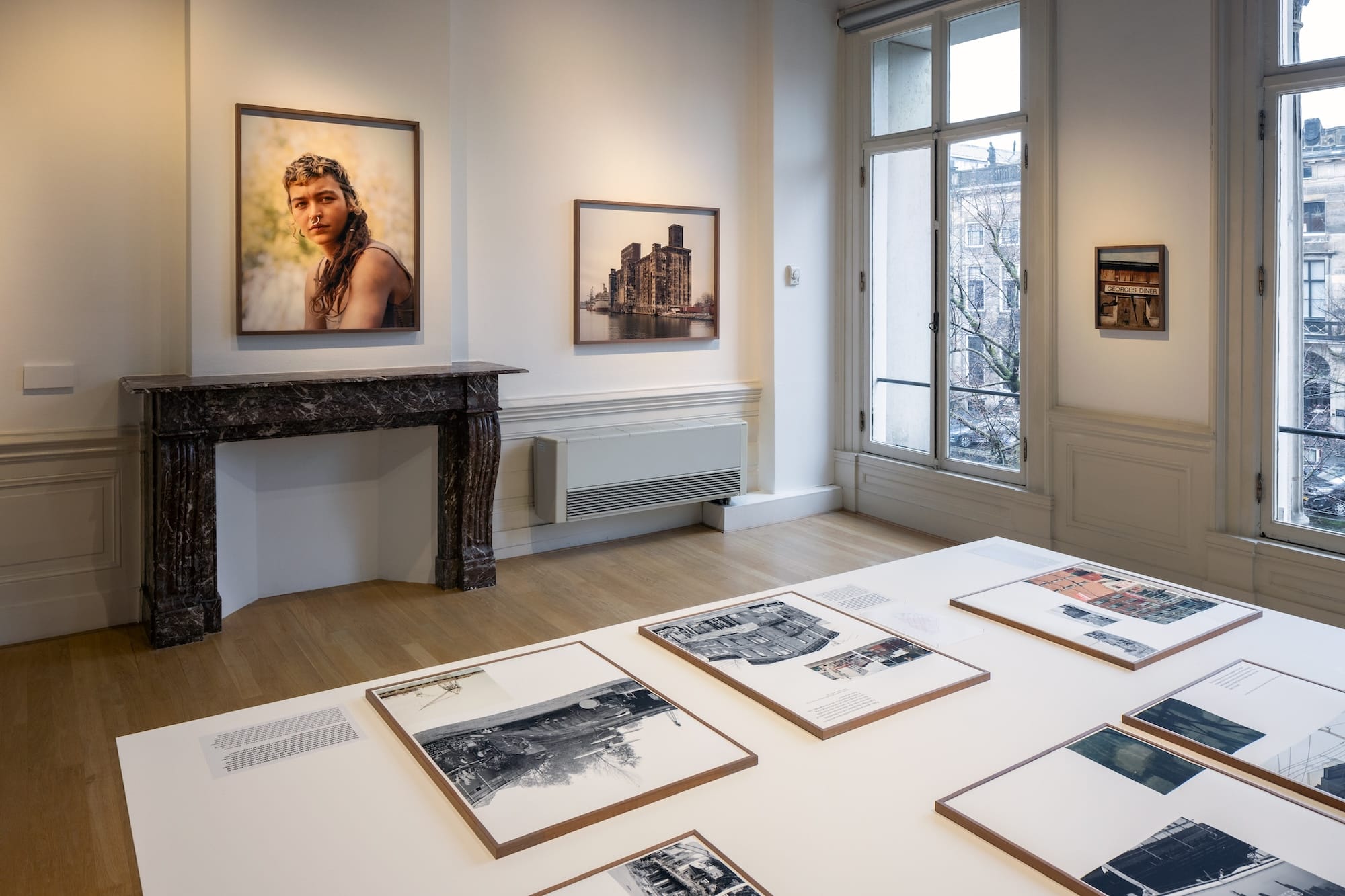 Image of an exhibition space, filled with artworks and an old fire place