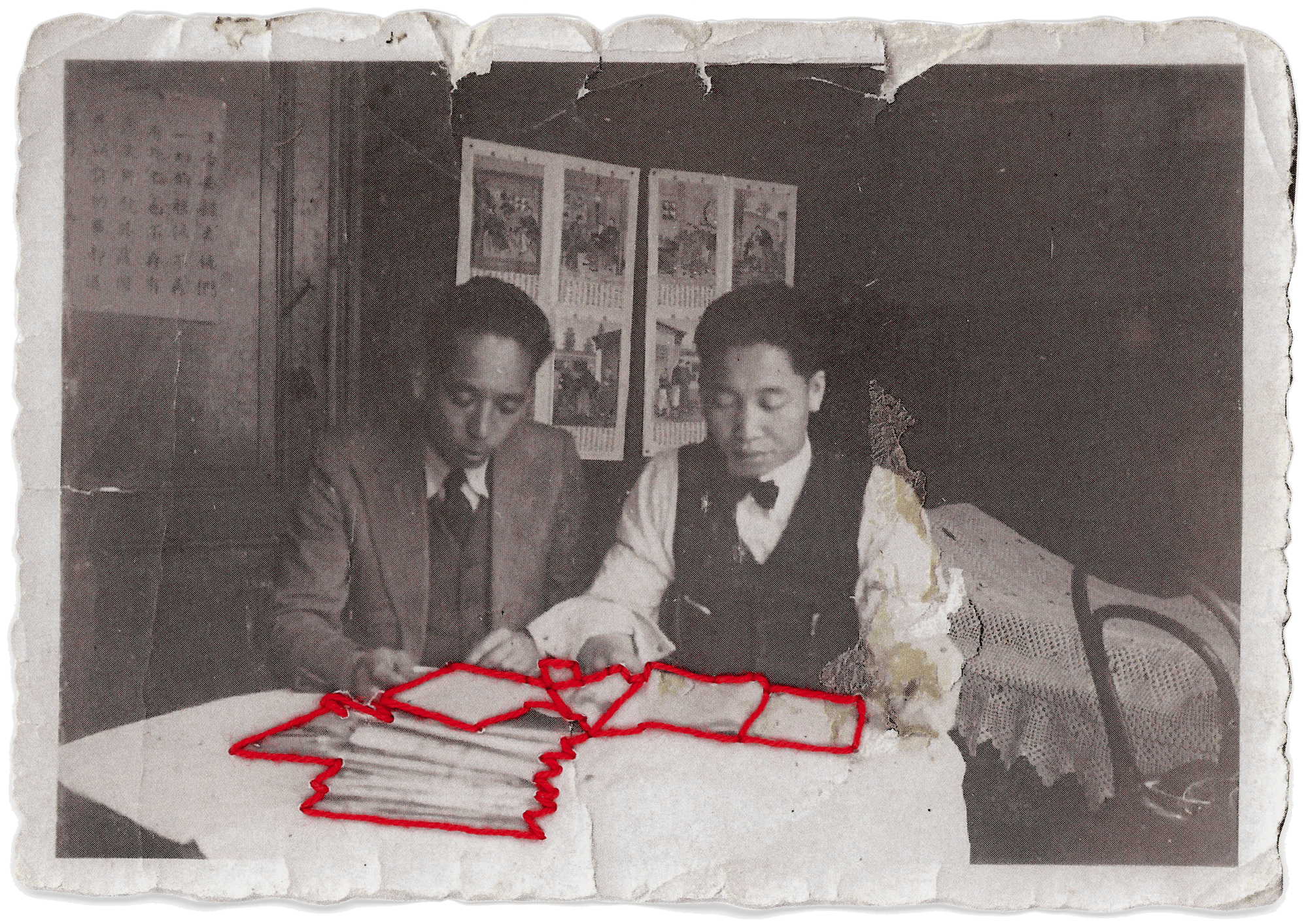 Black and white photograph of Laura Chen's grandfather in an office, with papers in front of him, which are sewn with red thread