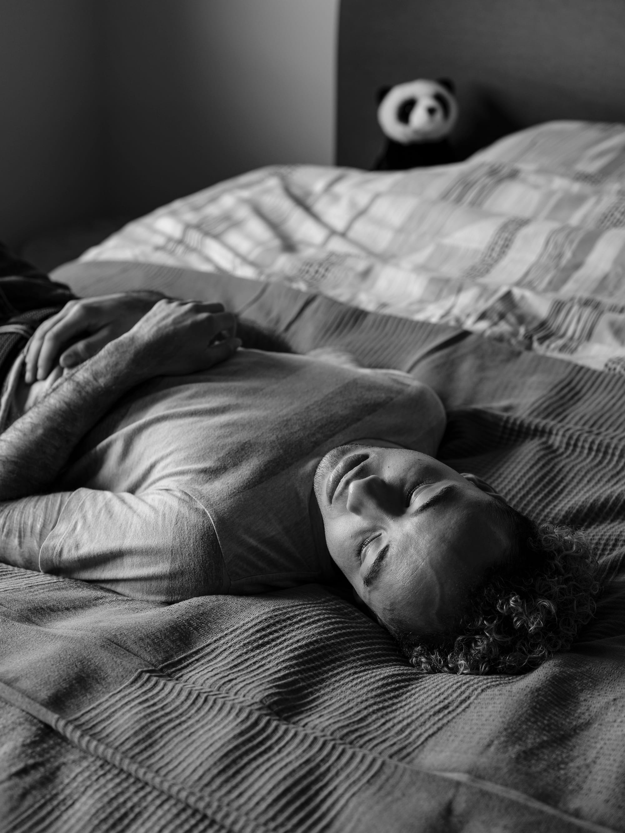 A black-and-white portrait of the photographer, Marvel Harris, lying on his bed.