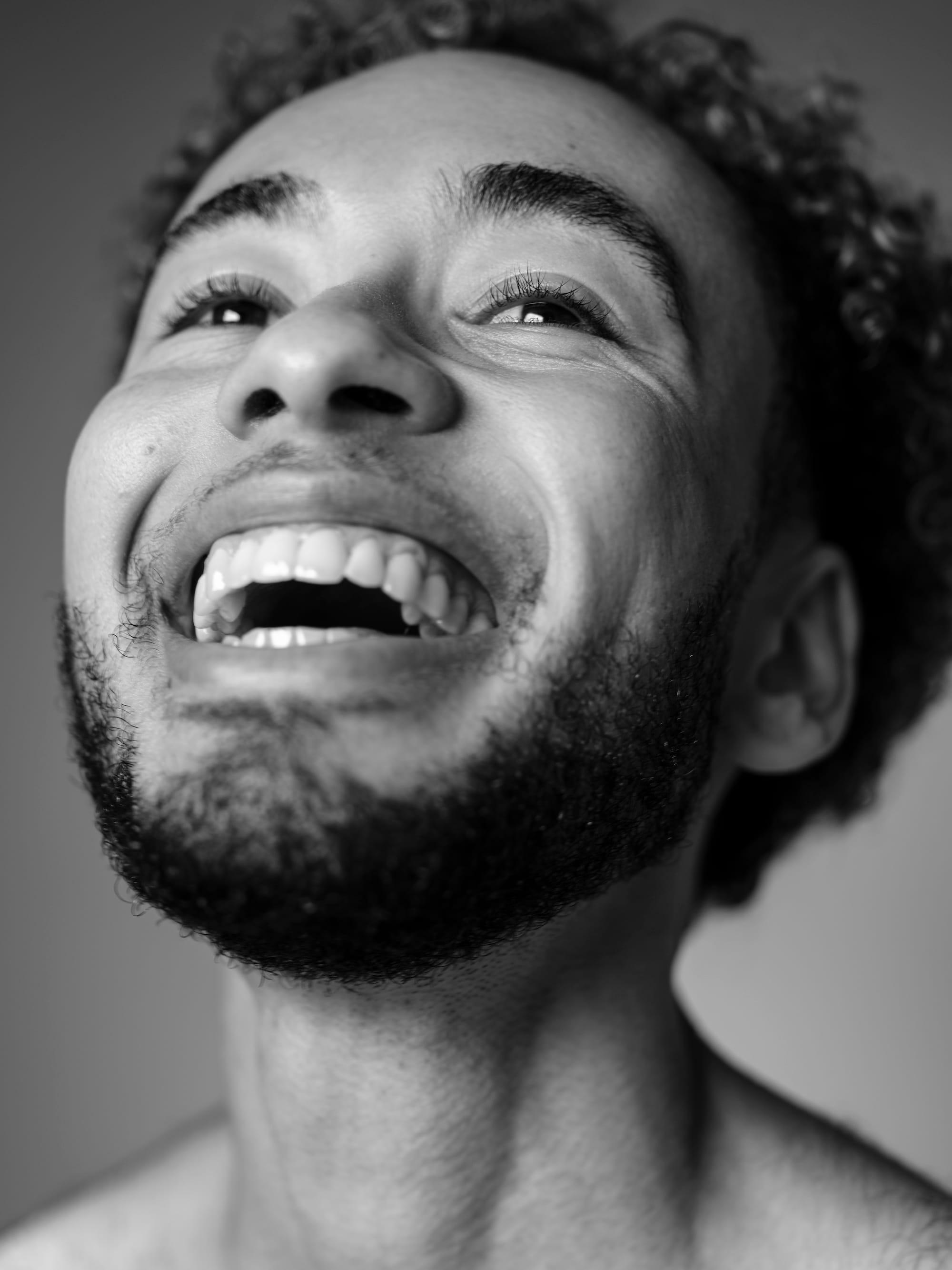 A black-and-white close-up portrait of the photographer, Marvel Harris, looking up and smiling brightly