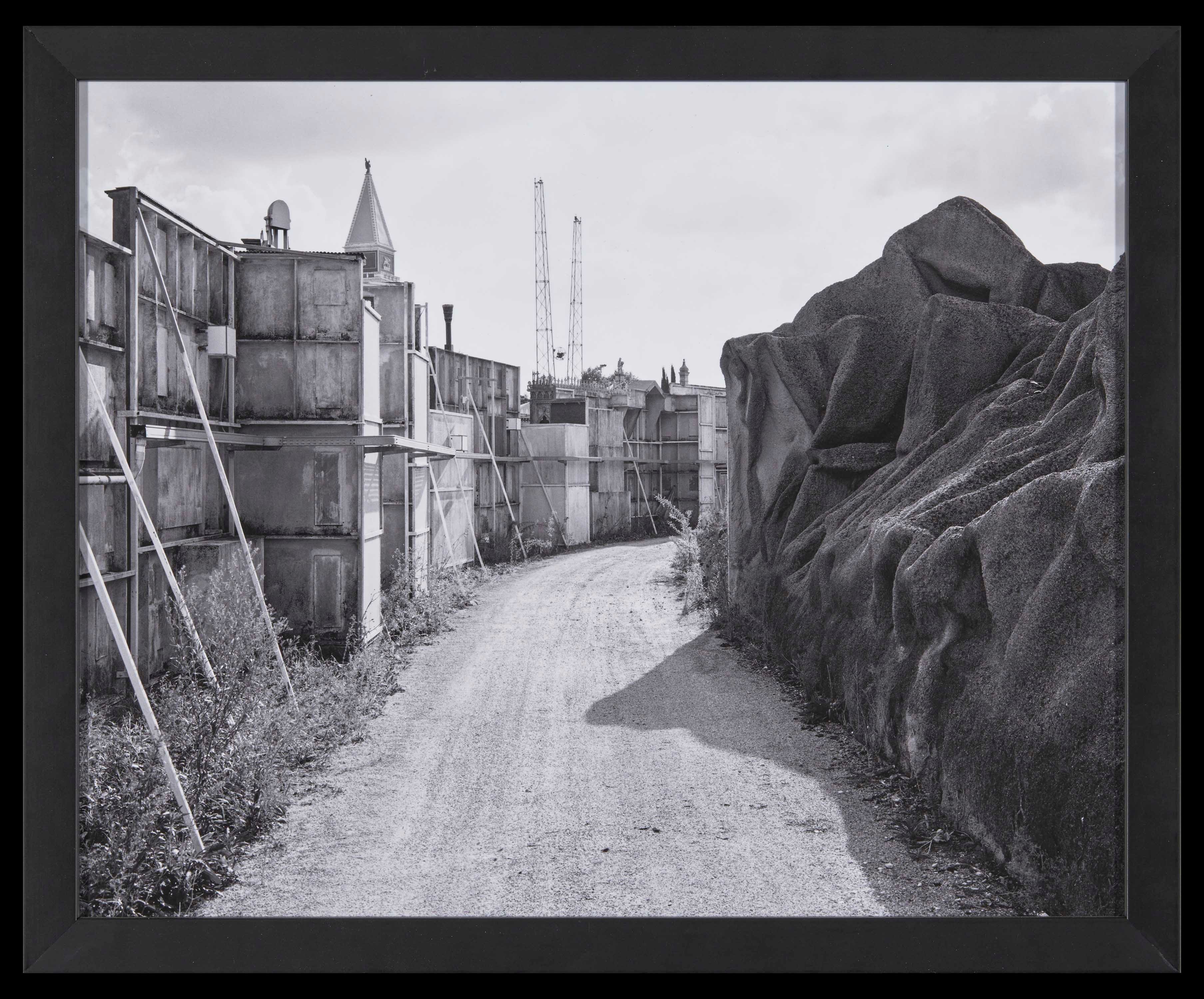 Black and white depiction of a narrow road, disappearing around the bend.