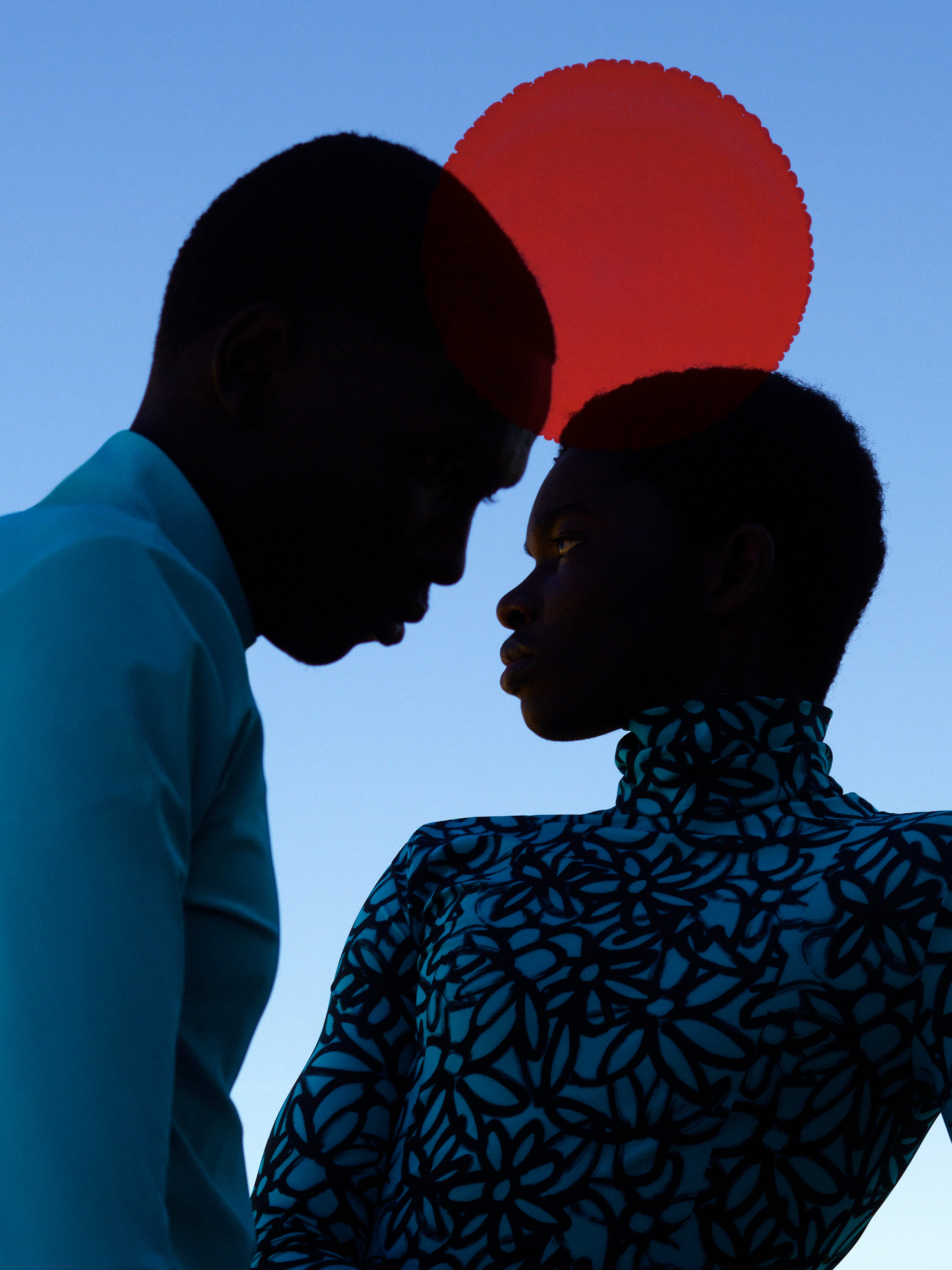 Two people looking to each other with a big red moon in the background