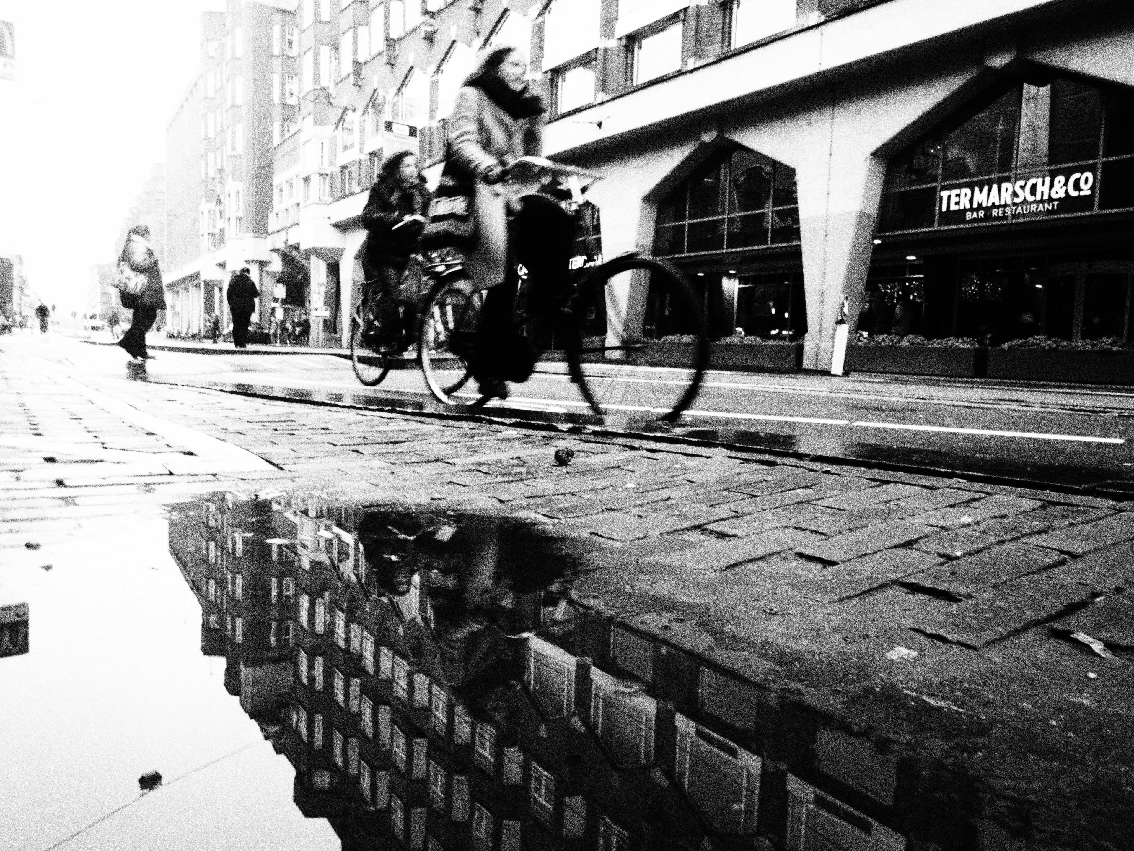 Black and white image of a woman biking in Amsterdam